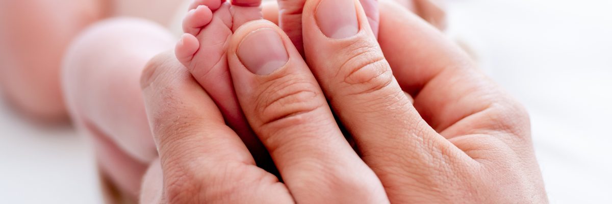 Mother holding newborn baby feet